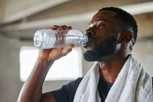 Image of man drinking water to improve hydration Cardiff after work out.